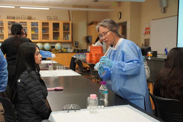 A teacher in a lab coat showing a student something in a test-tube