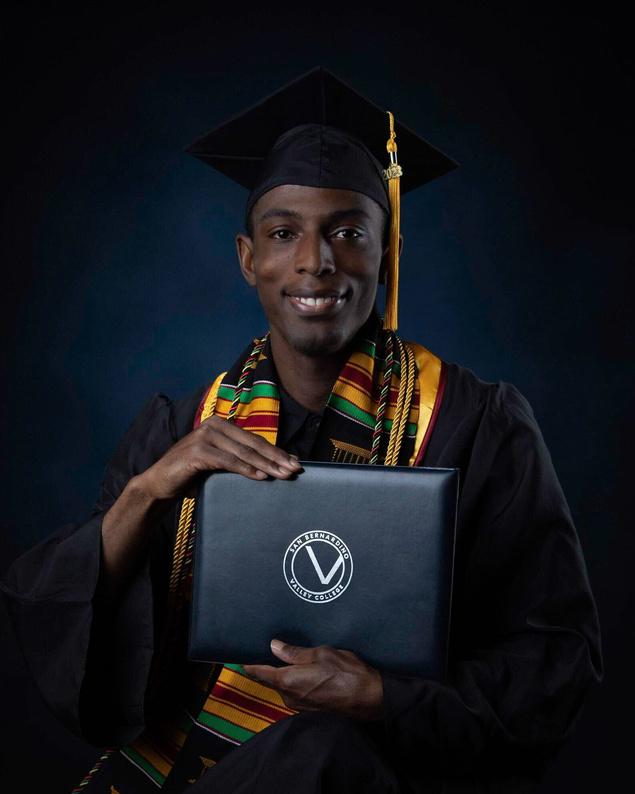 Headshot of Denmark Harris in a graduation gown holding his diploma