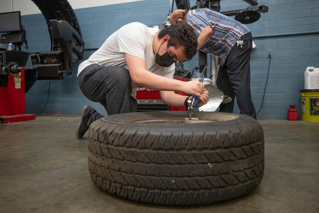 A student working with a tire in autoshop