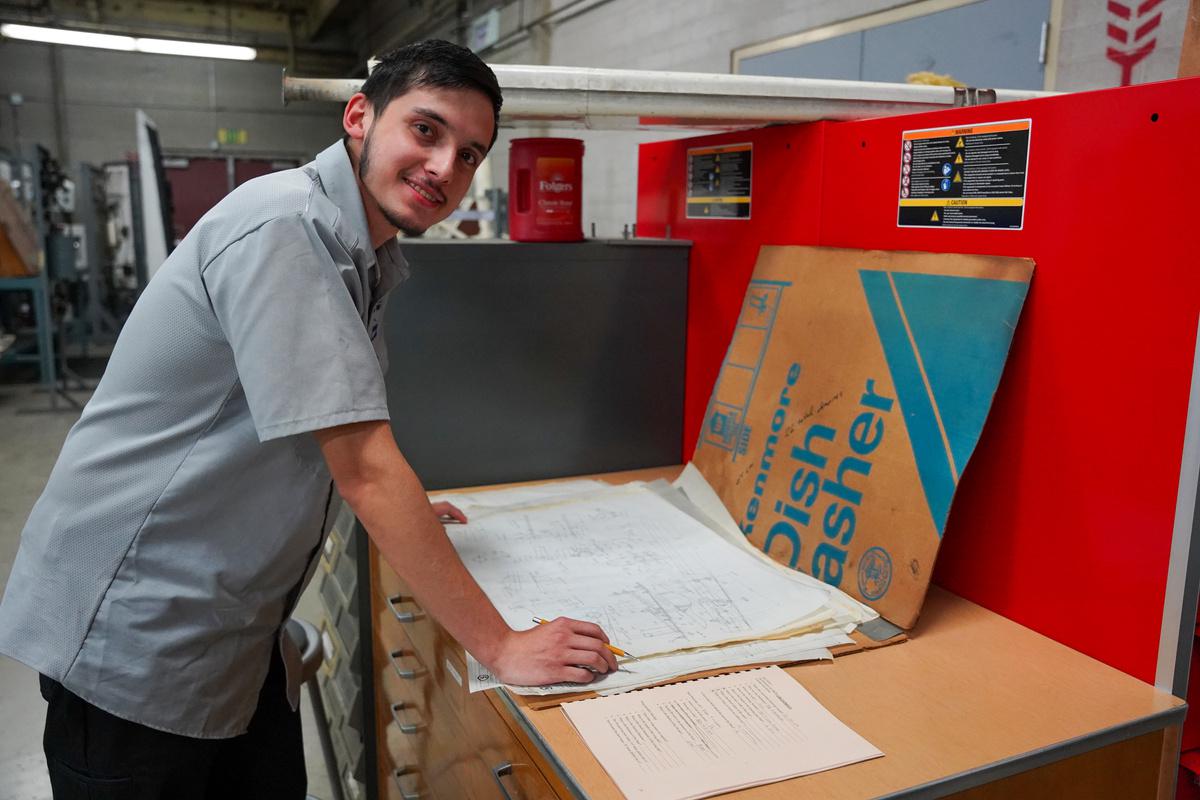 A student smiling for the camera after sketching out plans in autoshop