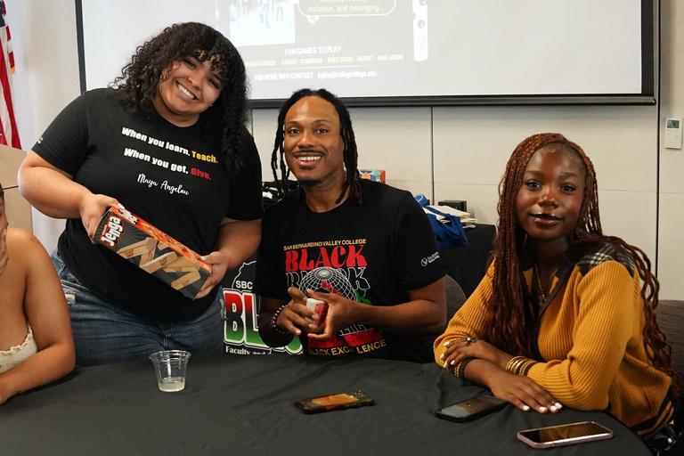 Students pose with Umoja coordinator Frederick Jones while playing board games